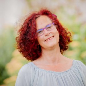 Lachende Frau mit roten lockigen Haaren und Brille