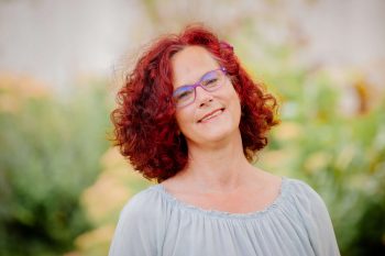 Lachende Frau mit roten lockigen Haaren und Brille