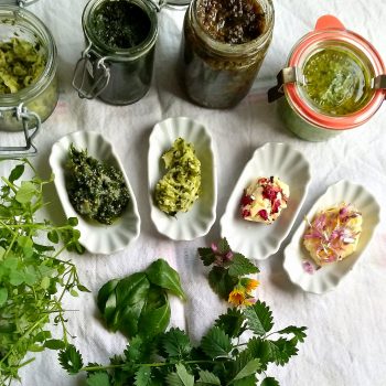 4 Schälchen und Gläser mit verschiedenen Wildkräuter-Pestos dekoriert mit ffrischen Wildkräutern