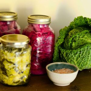 Drei Gläser mit fermentiertem Gemüse, eine schale Salz und ein Wirsingkopf